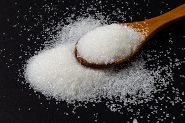 Sugar on a surface being collected on a wooden spoon