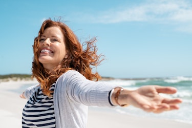 A middle aged lady running happily on the beach
