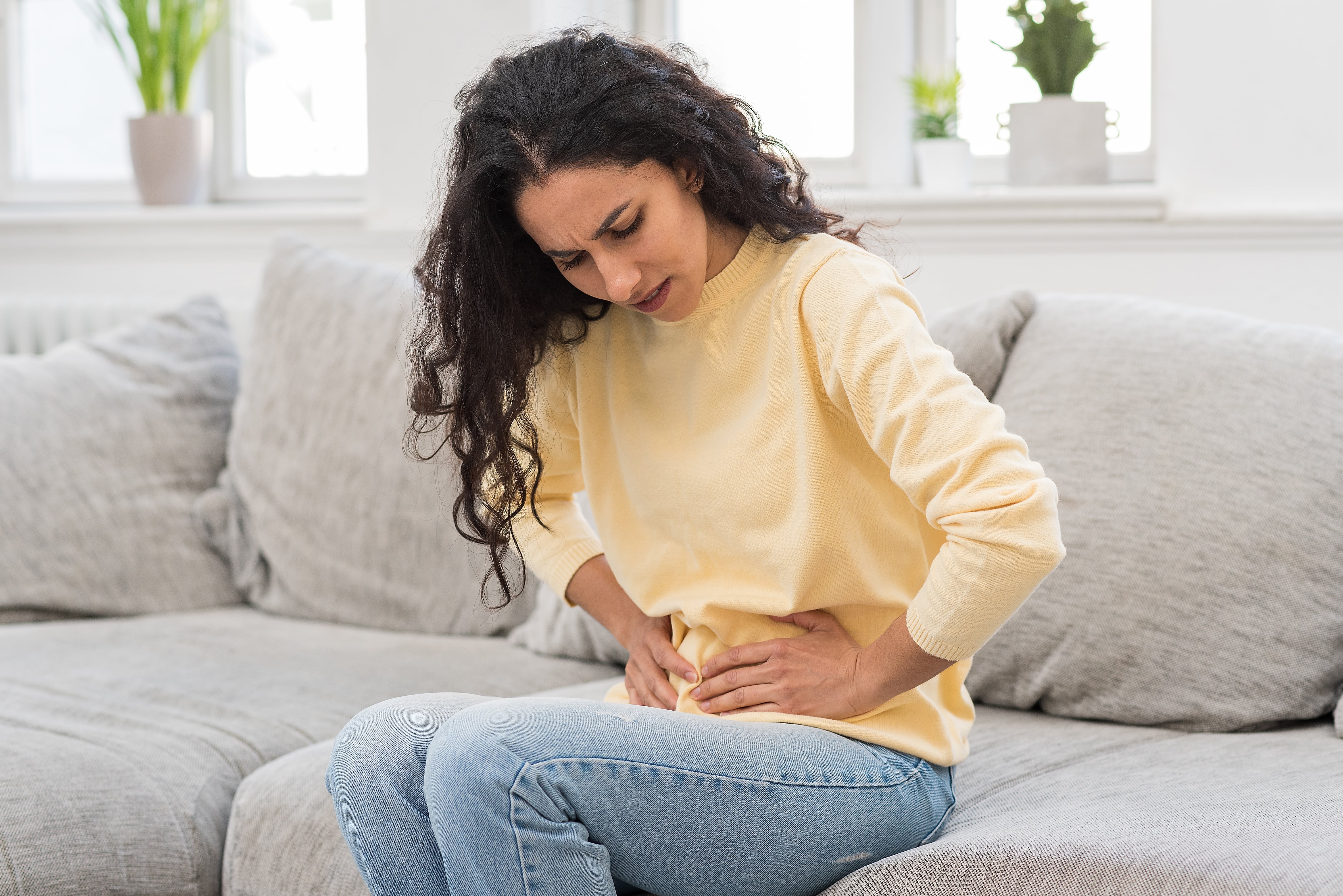 A lady experiencing constipation whilst sat on the sofa