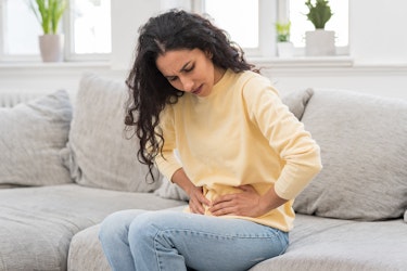 A lady experiencing constipation whilst sat on the sofa