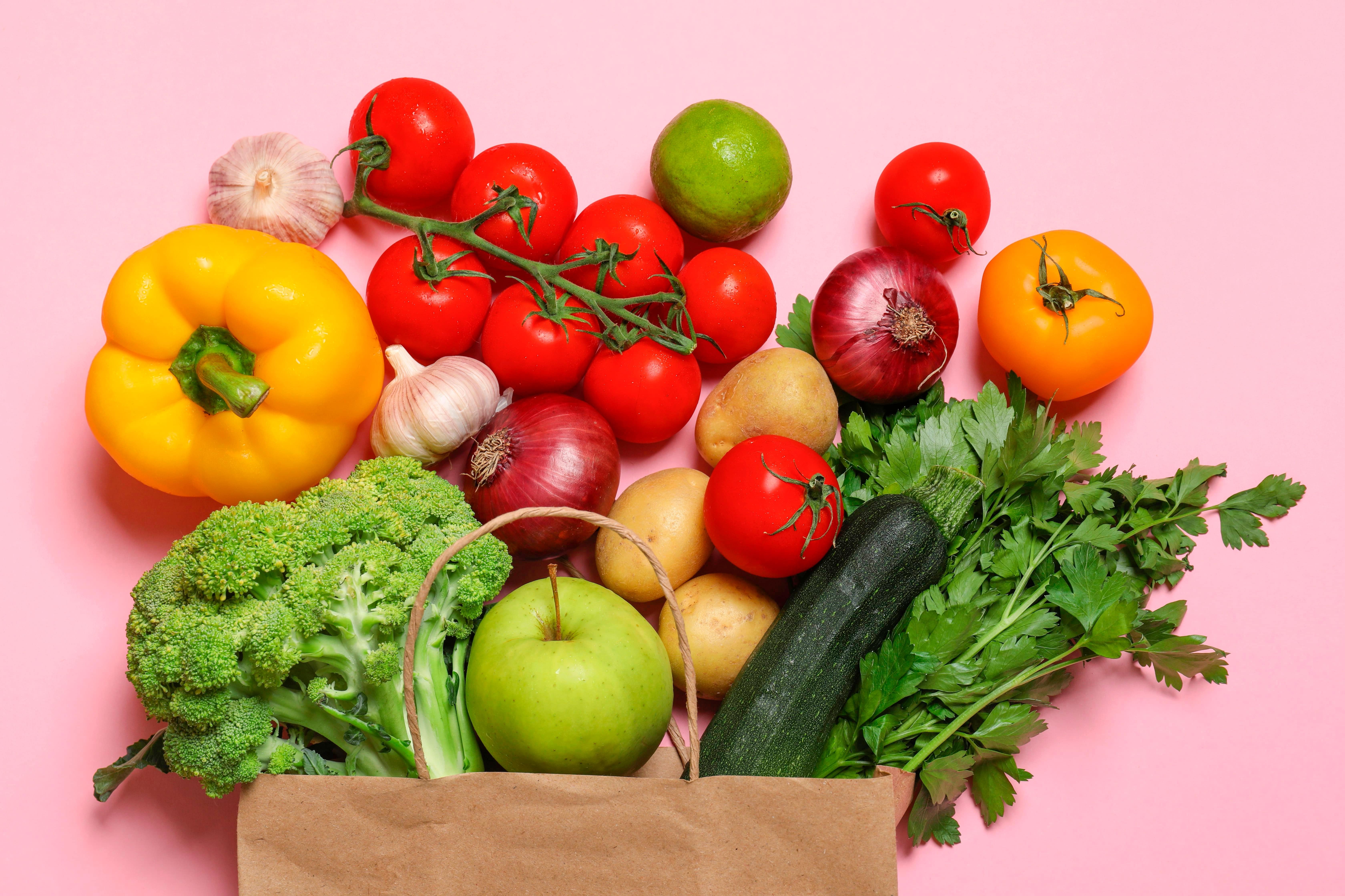 Various healthy vegetables pouring out of a paper bag