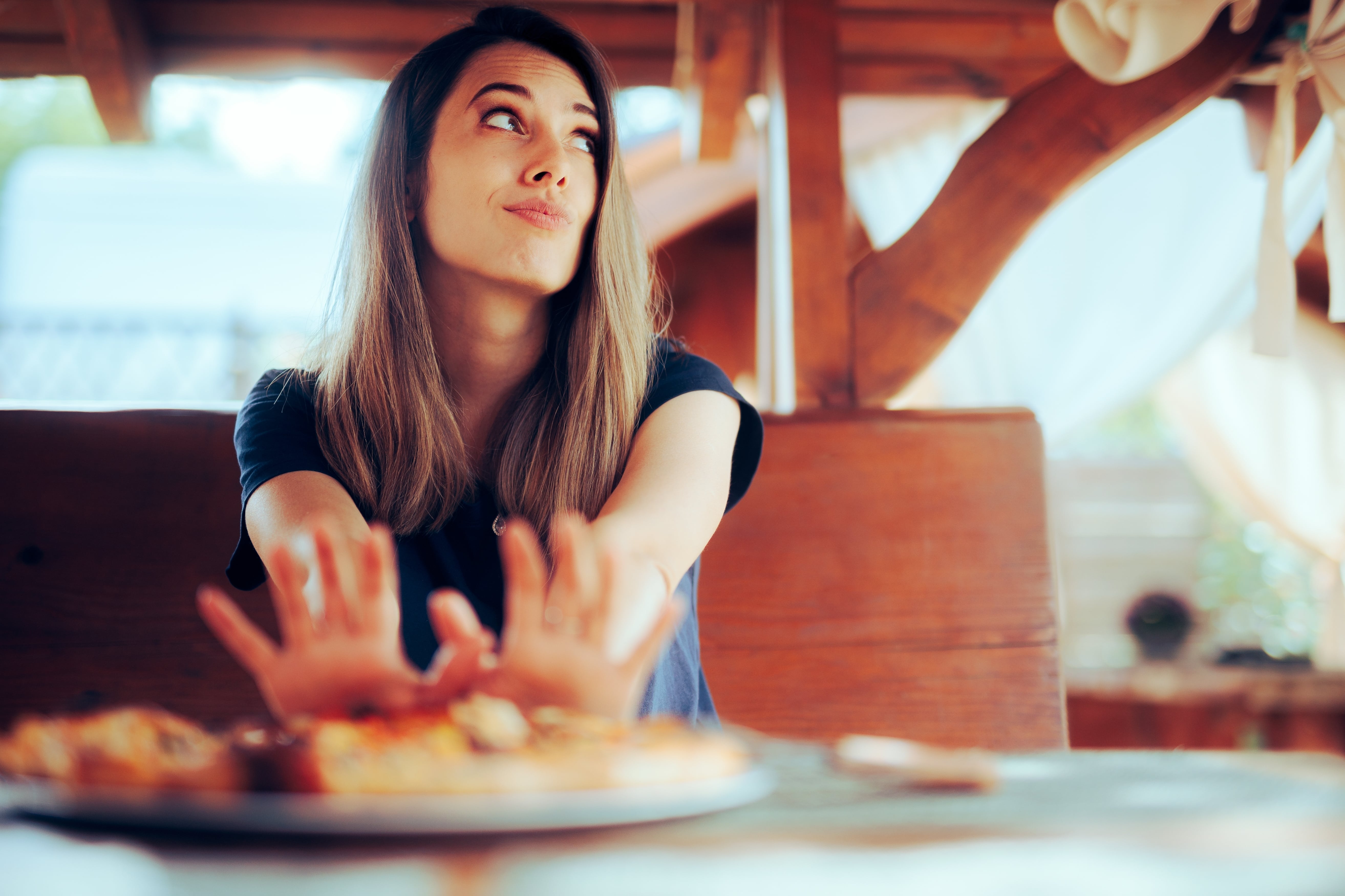 A lady refusing to eat food that is on a plate in front of her