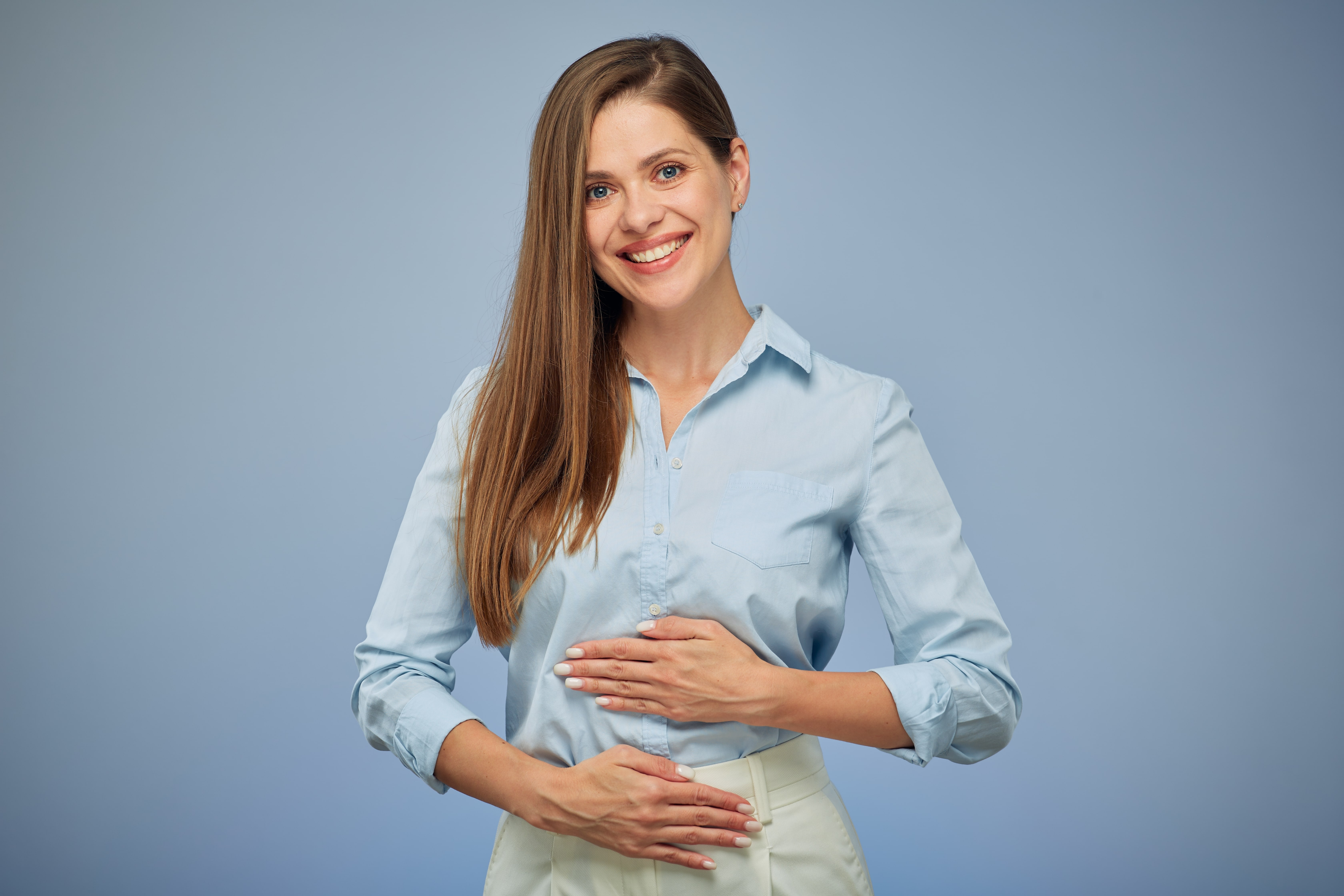 A lady smiling whilst holding her stomach to indicate that she has a happy gut