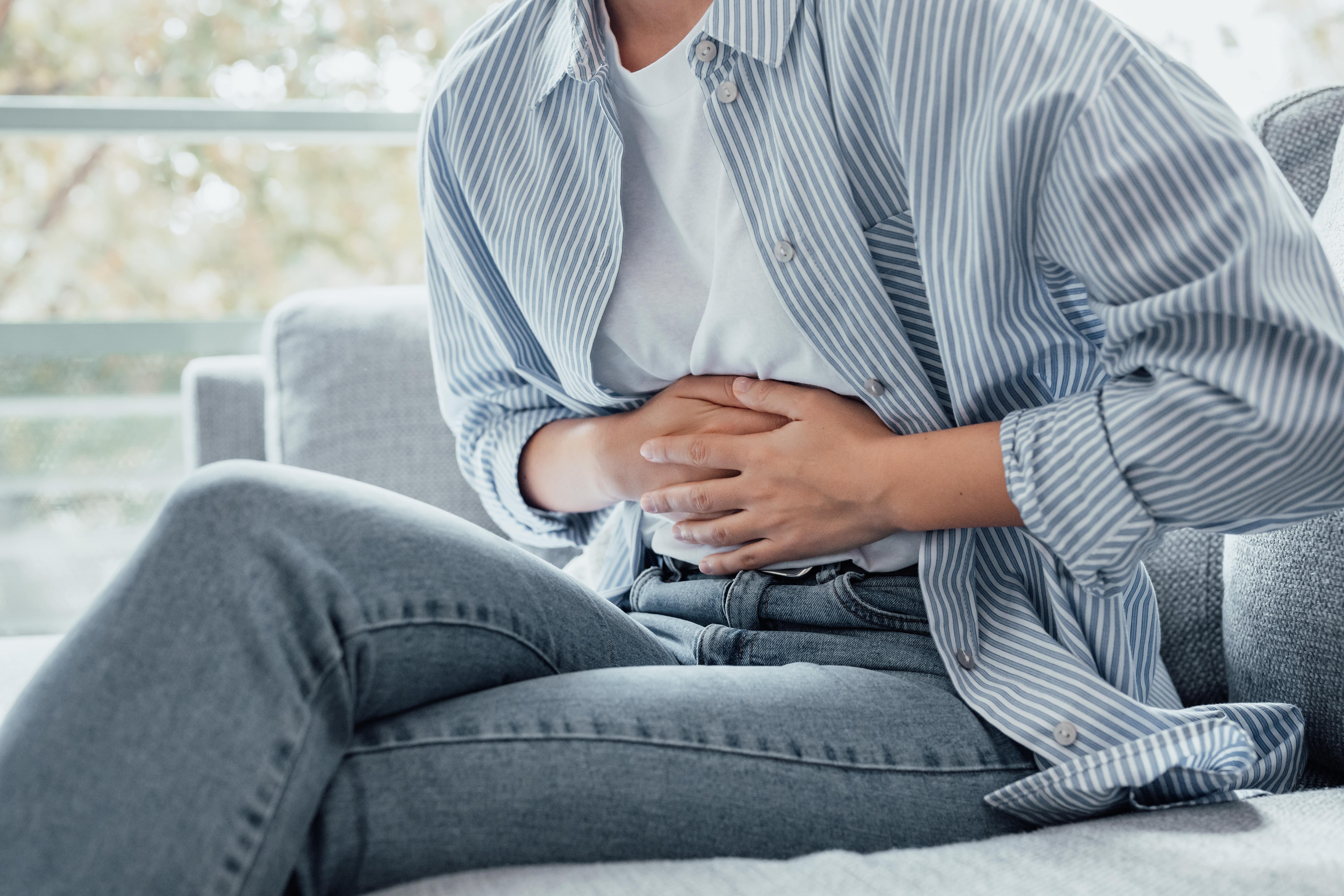 A person clutching their stomach to indicate discomfort in their gut
