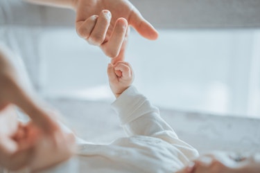 An adult hand reaching out to a newborn baby's hand