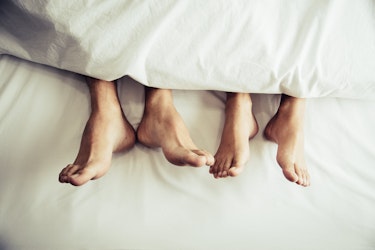 Couple’s feet under a duvet, symbolising intimacy and connection in a discussion about how NAD+ may support sexual wellness and energy.