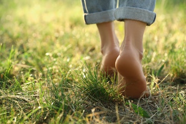 Person walking barefoot on grass, illustrating the calming and grounding effects of earthing for better wellbeing and stress relief.