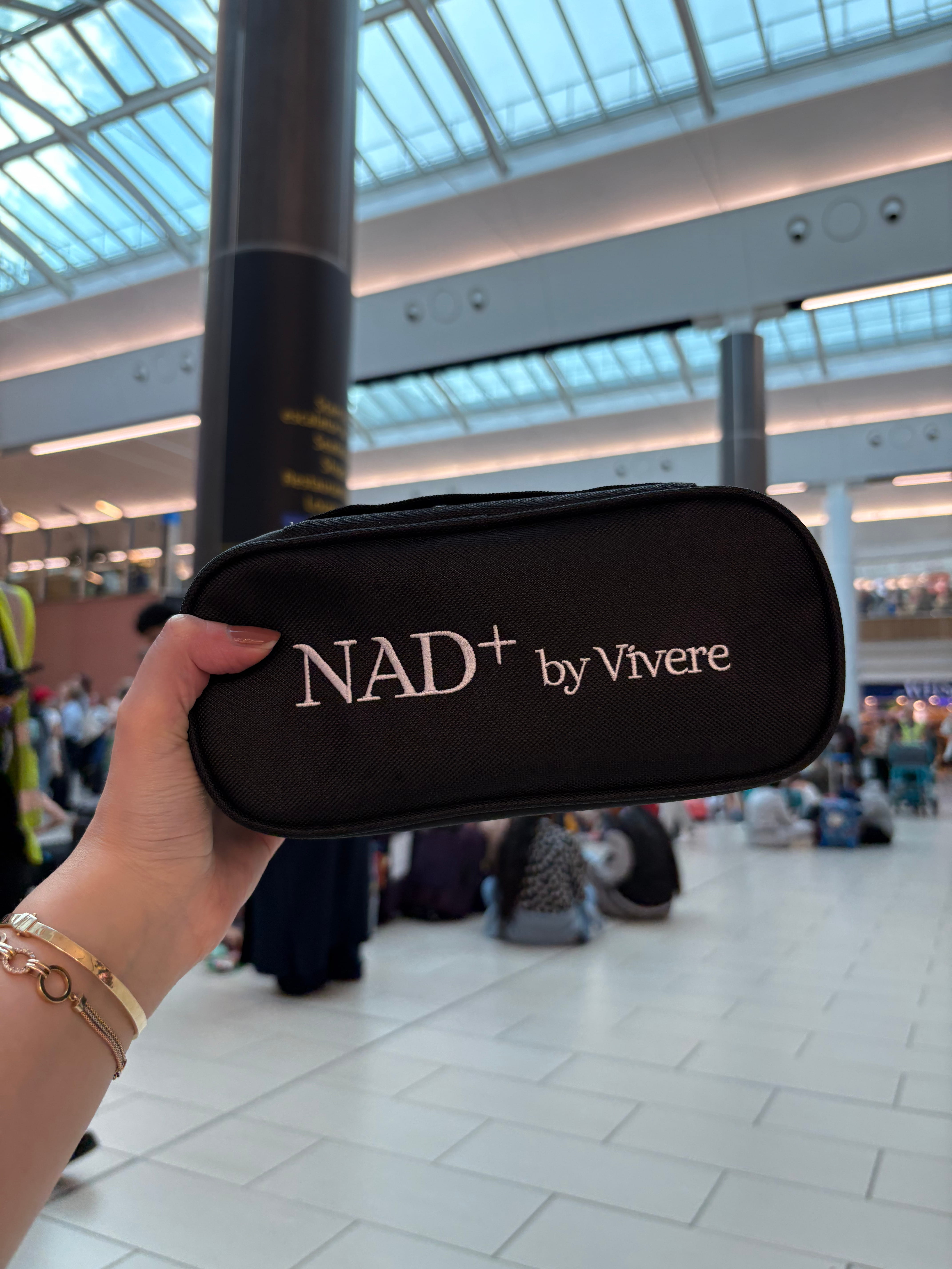 A Vivere NAD+ travel pouch held at an airport, showing how you can safely take your pen through security