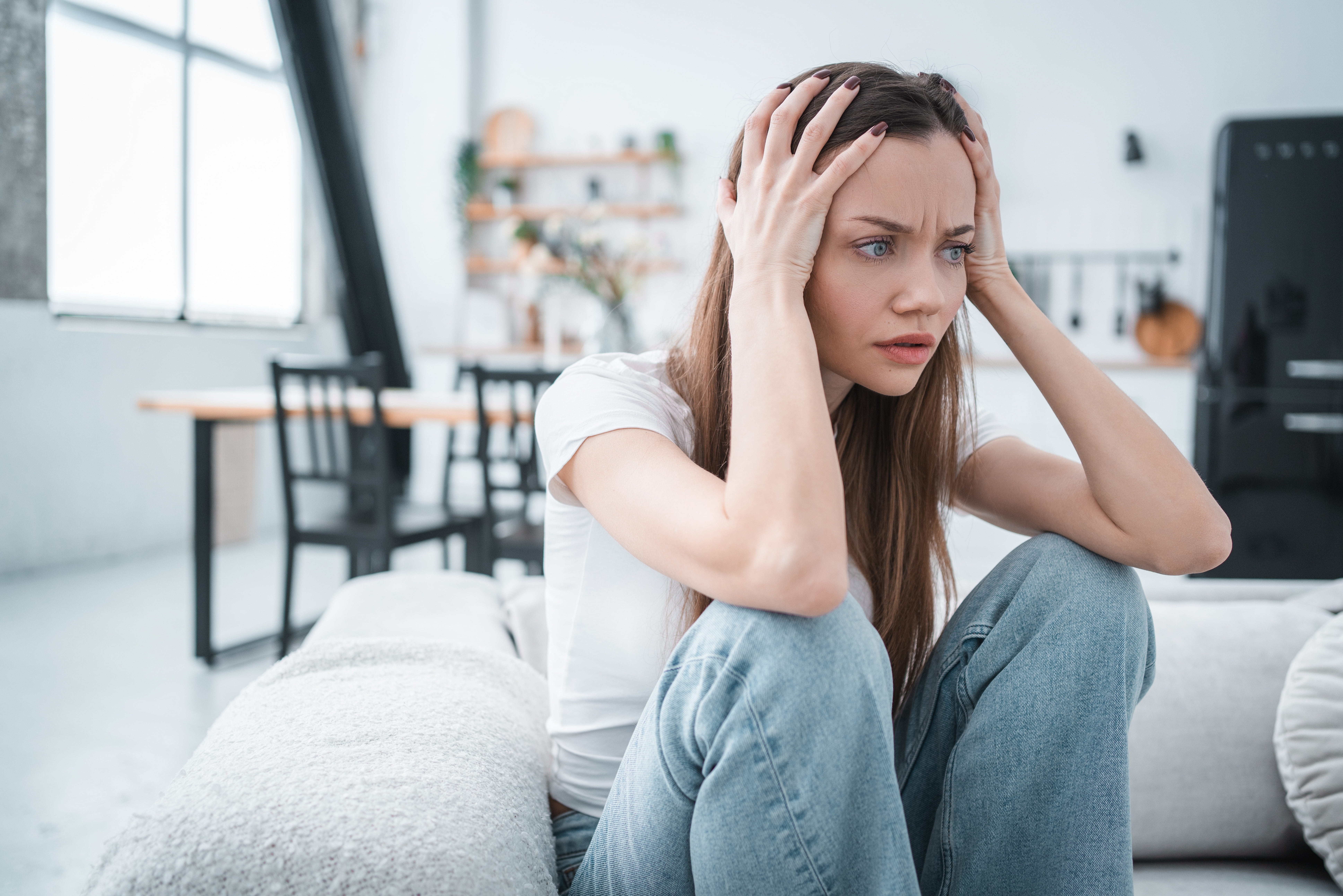 Woman holding her head with both hands, looking anxious and overwhelmed