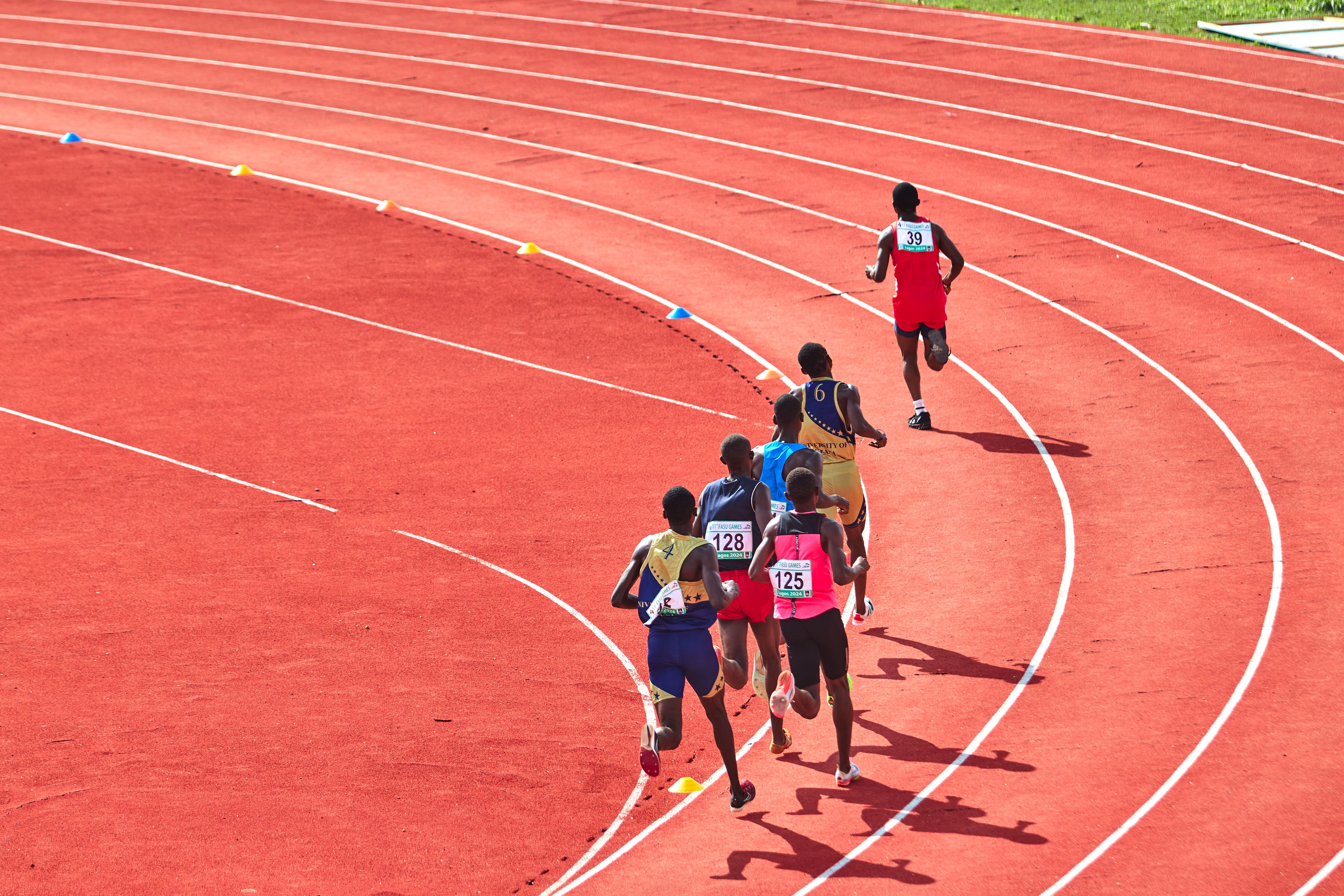 Group of runners racing round the bend of an outdoor athletics track on a sunny day