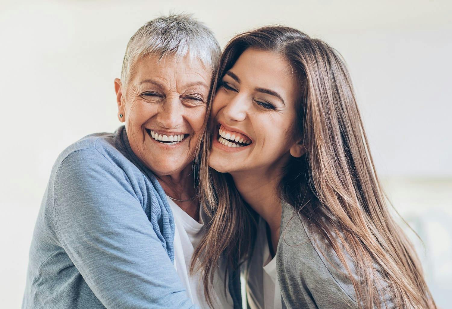 Two woman smiling while resting their heads together