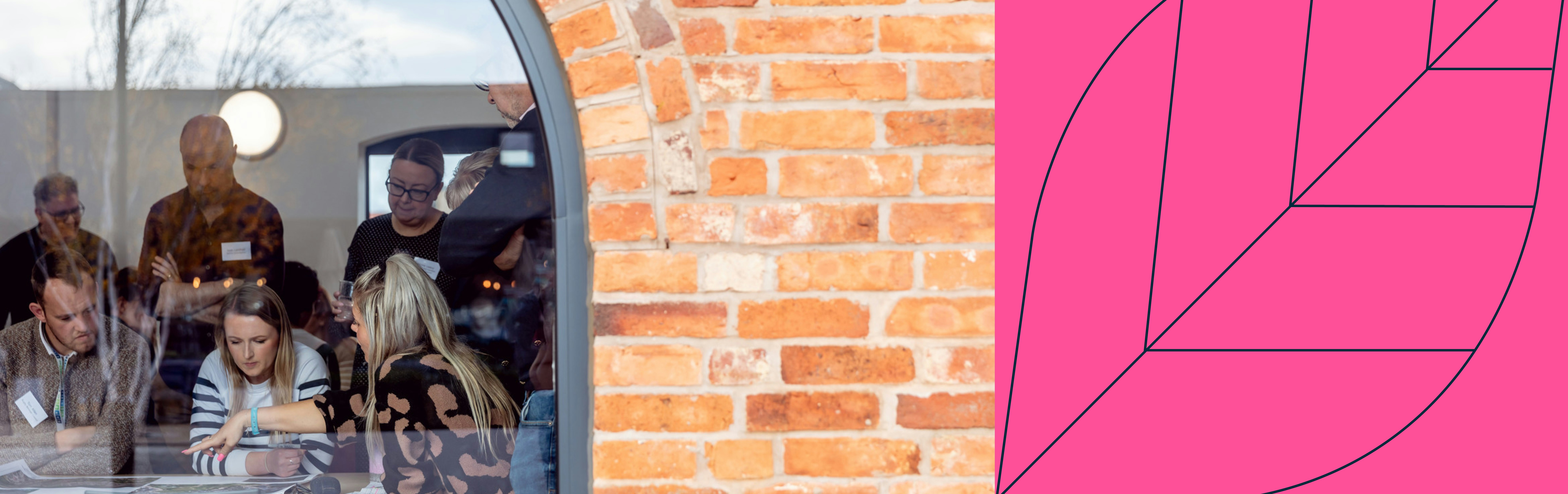 People behind glass with brick wall and pink motif