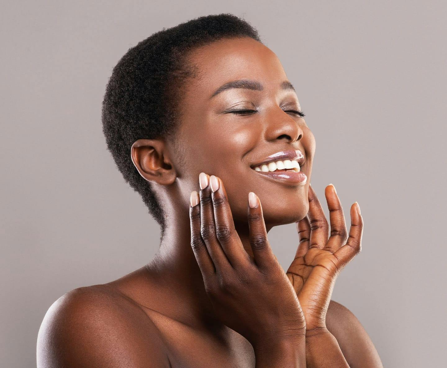 woman with short hair smiling and touching her cheeks