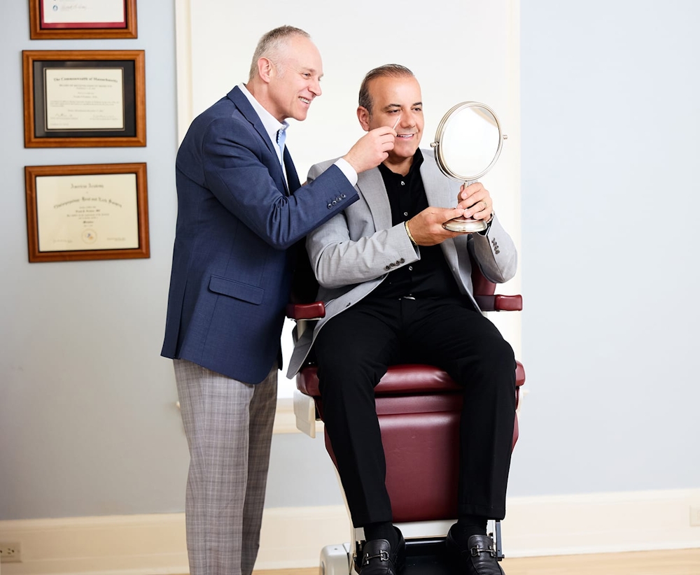 Dr. Fechner point to client's nose while he looks in handheld mirror