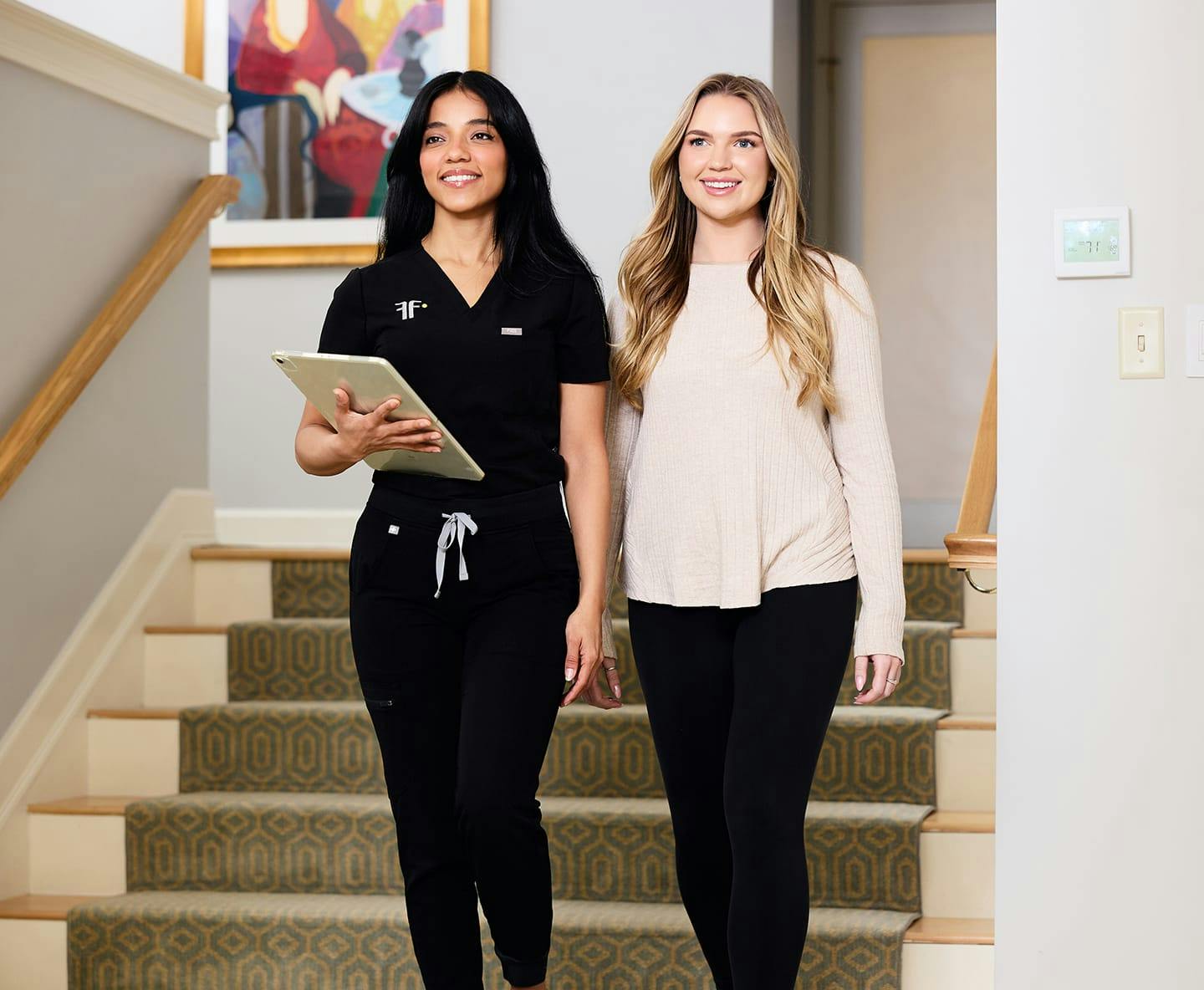 patient walking with nurse thats holding an ipad