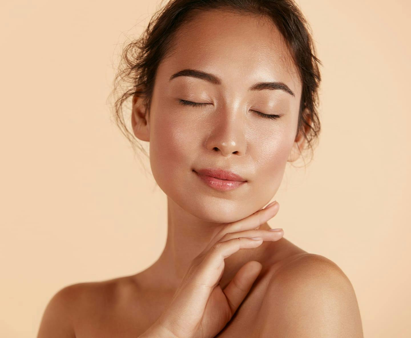 woman with eyes closed touching her chin