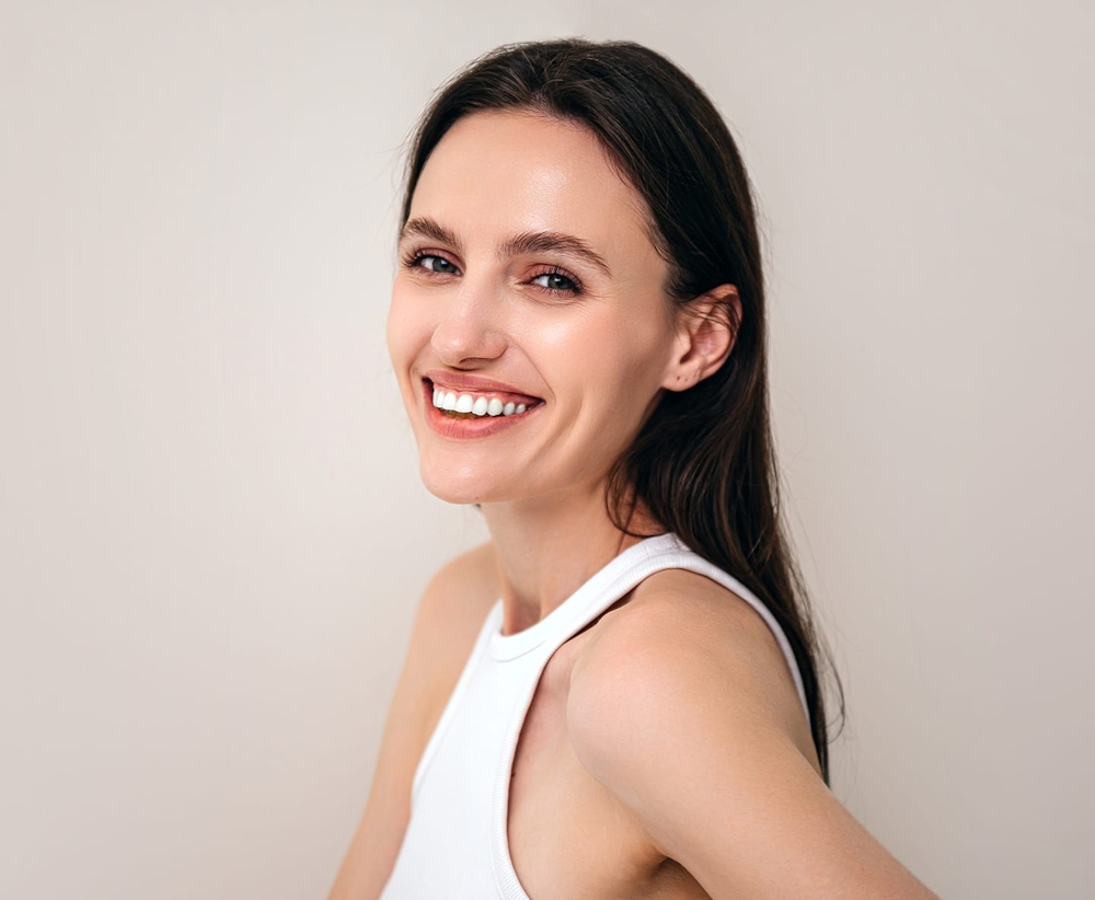 woman in white tanktop smiling