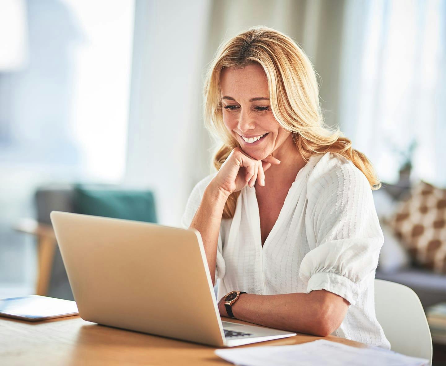 woman sitting at table looking at laptop