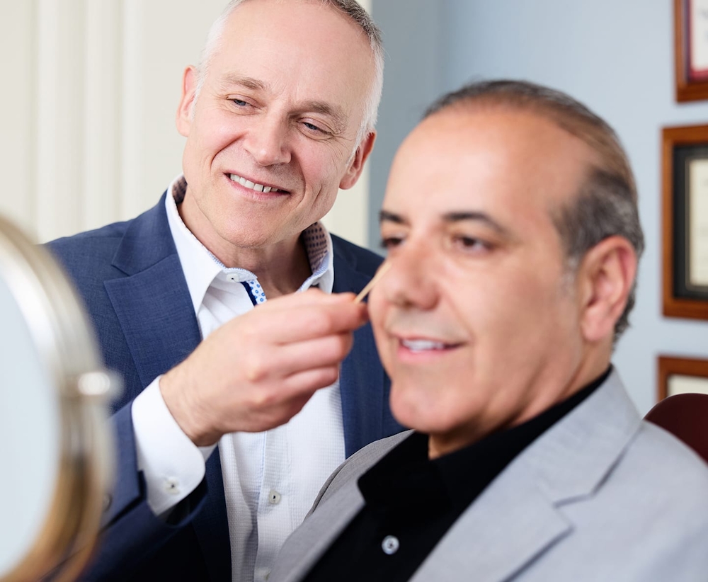 Dr. Fechner pointing to male patient's nose