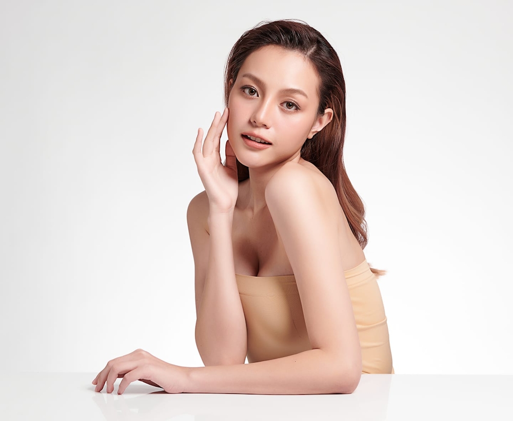 asian woman leaning on table with hand touching her face