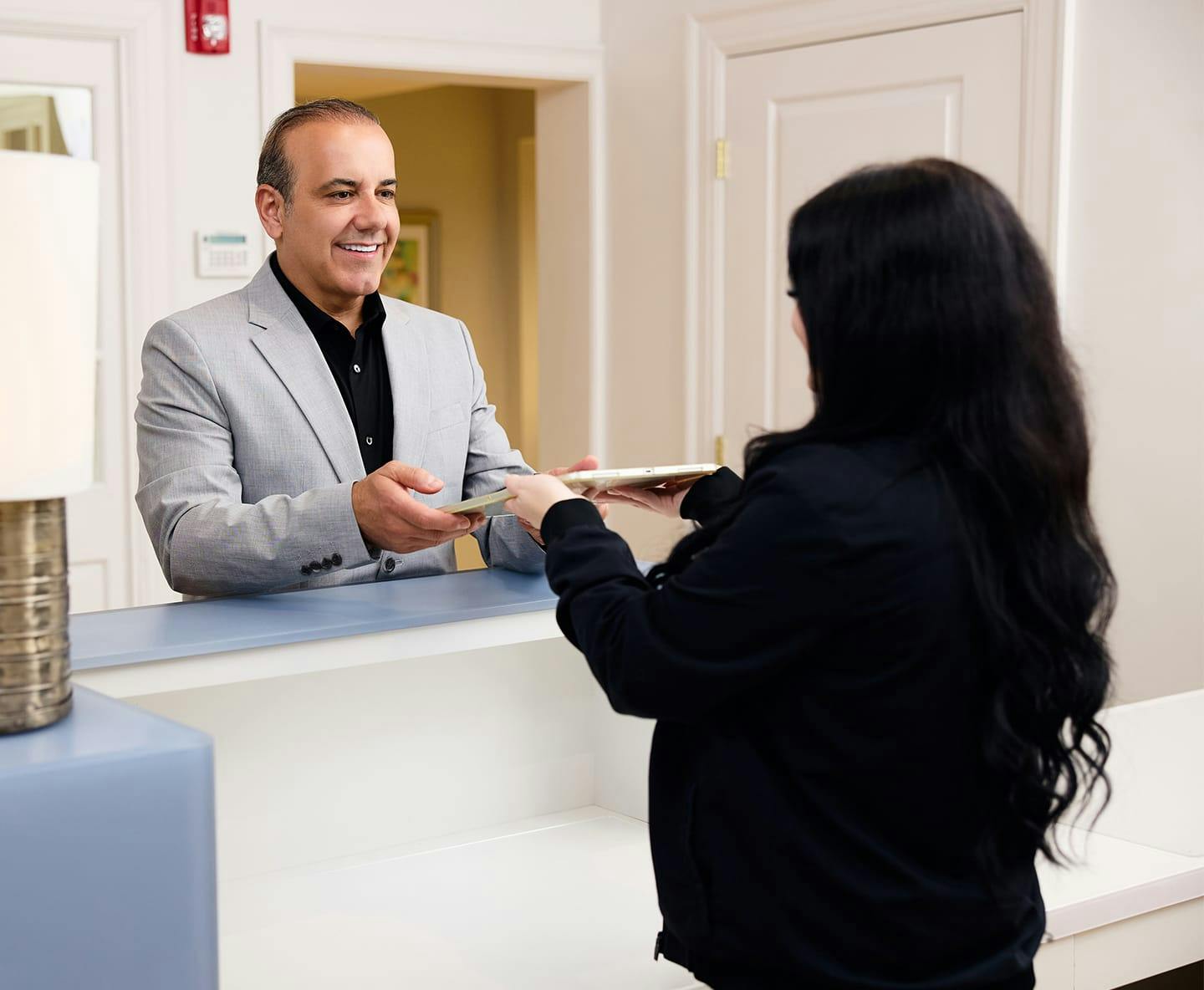 receptionist handing ipad to male patient