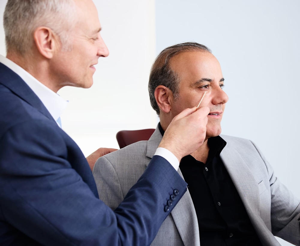 Dr. Fechner pointing to male patient's undereyes