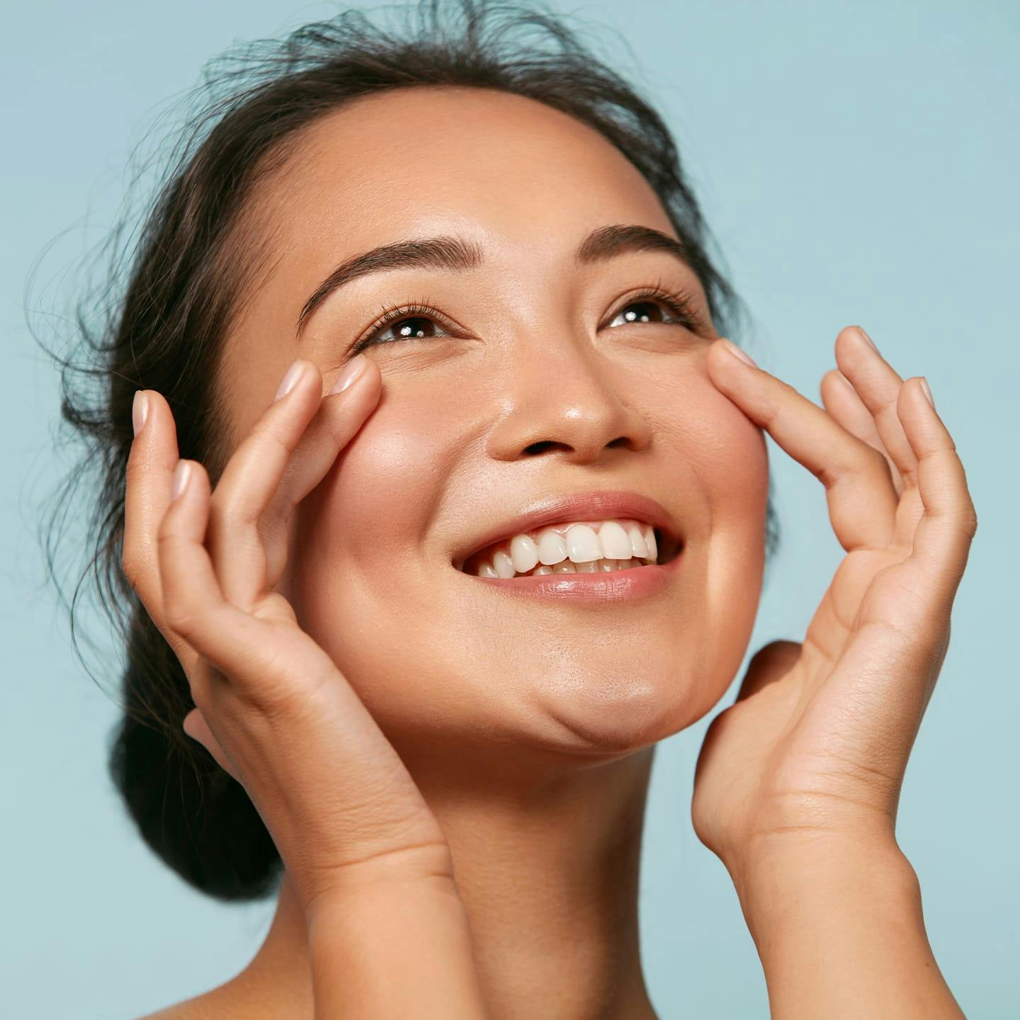 woman smiling with her fingers touching both of her cheeks