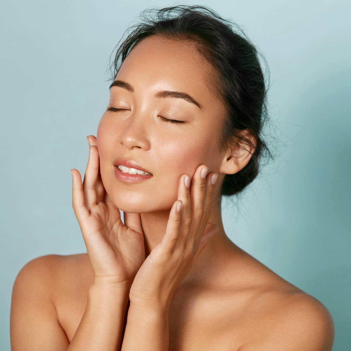 woman with her eyes closed and touching her cheeks