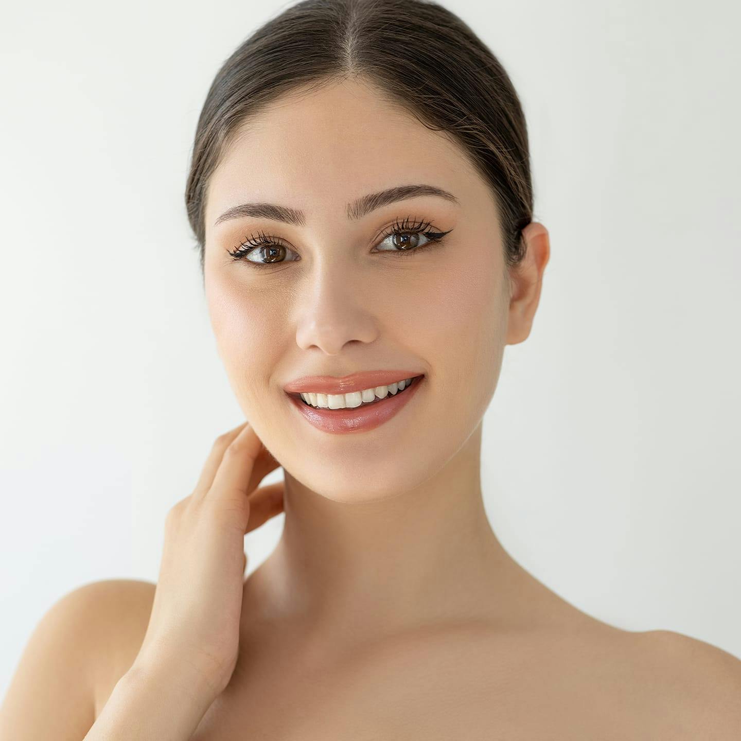 woman with hair tied back with hand on her neck