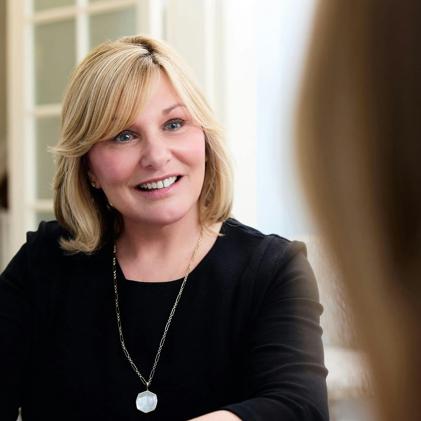 patient in black shirt with necklace smiling
