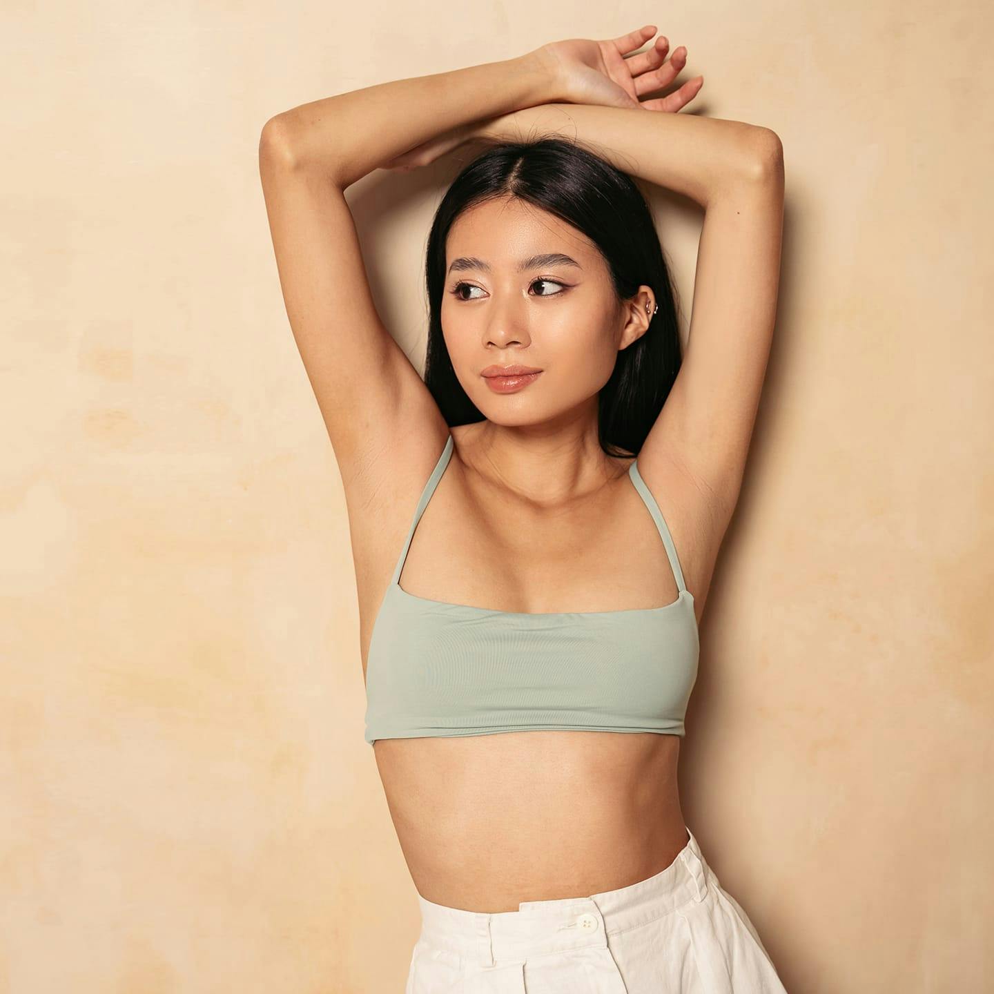 woman in sports bra with her arms above her head