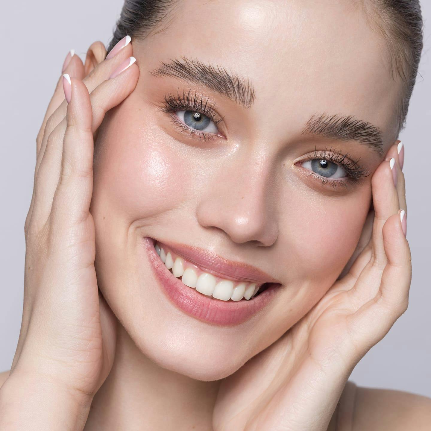close up of woman's face smiling and touching her temples