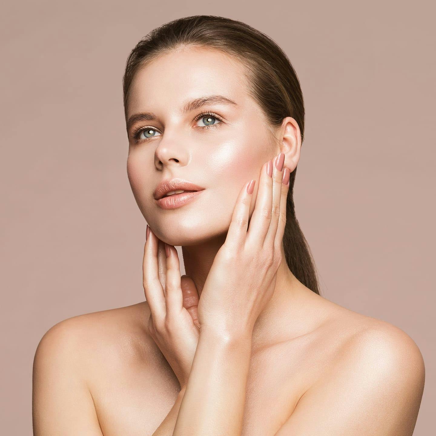 woman with slick back hair touching her face with her hands