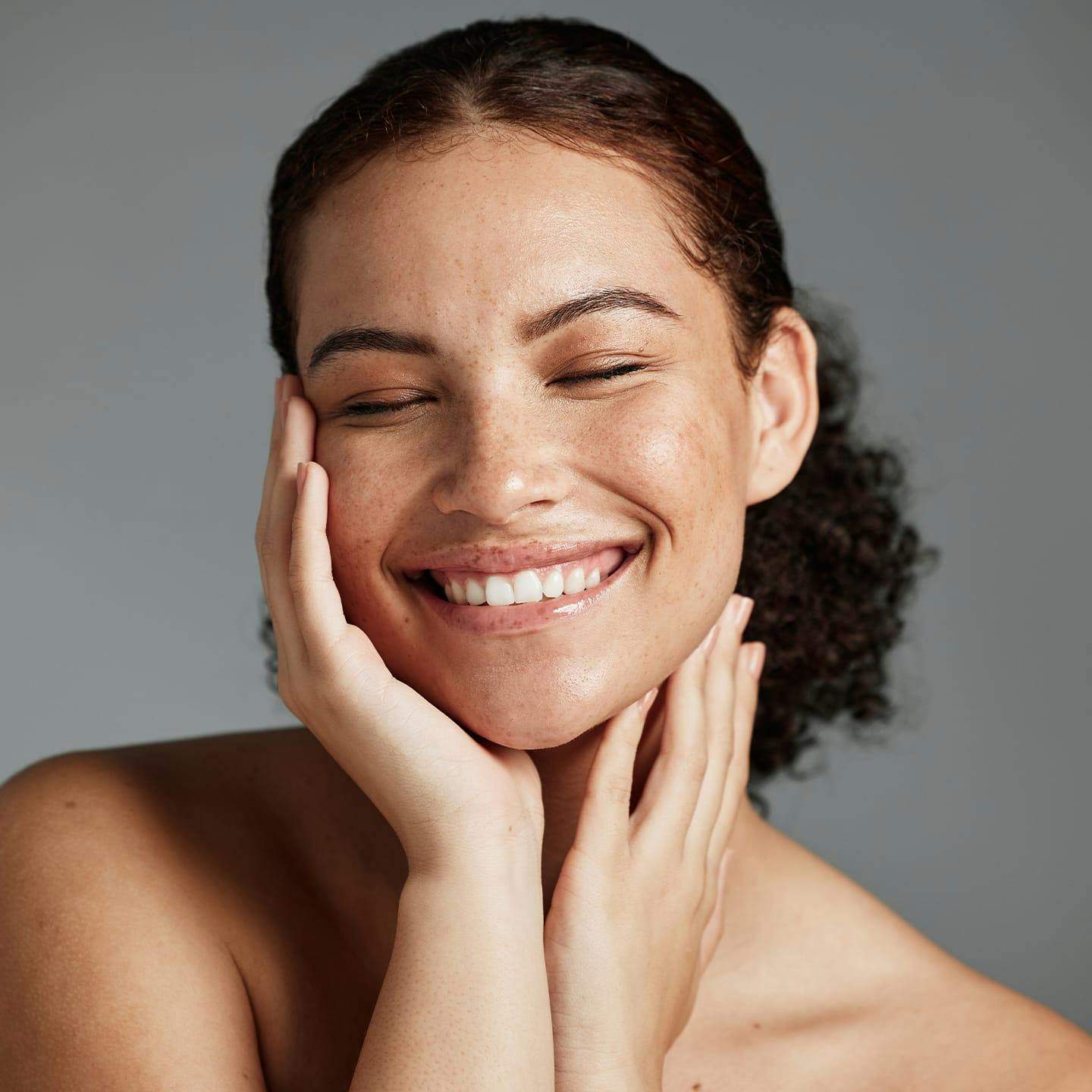 woman with curly hair with her hands touching her face