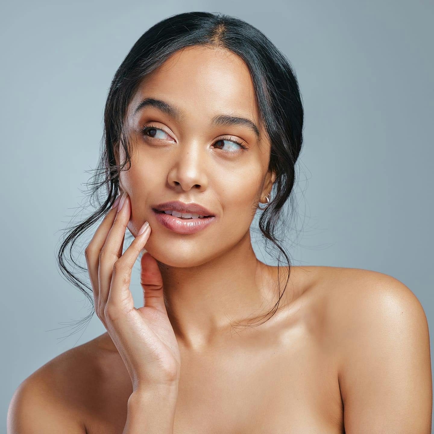 woman touching one side of her face as she looks to the left