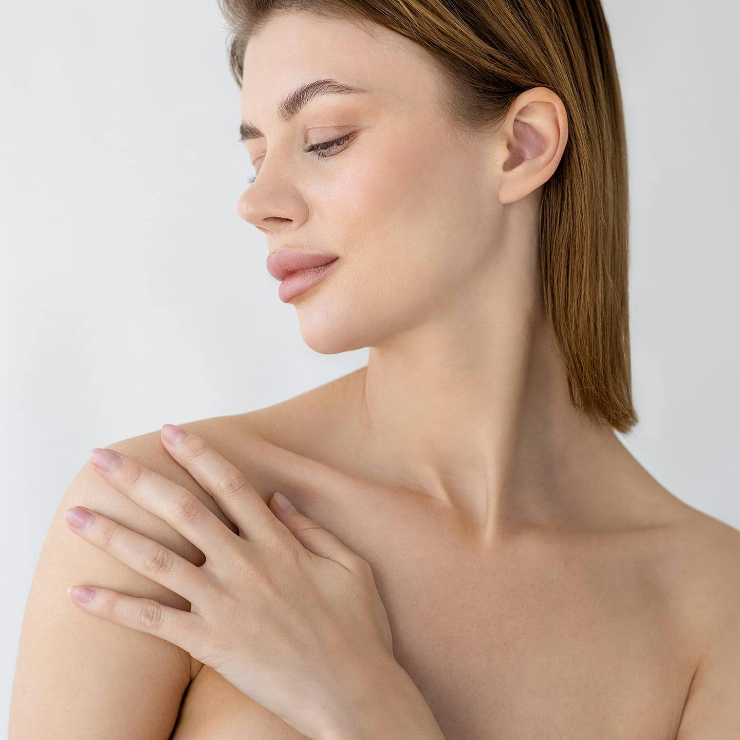 woman touching her shoulder looking down at it
