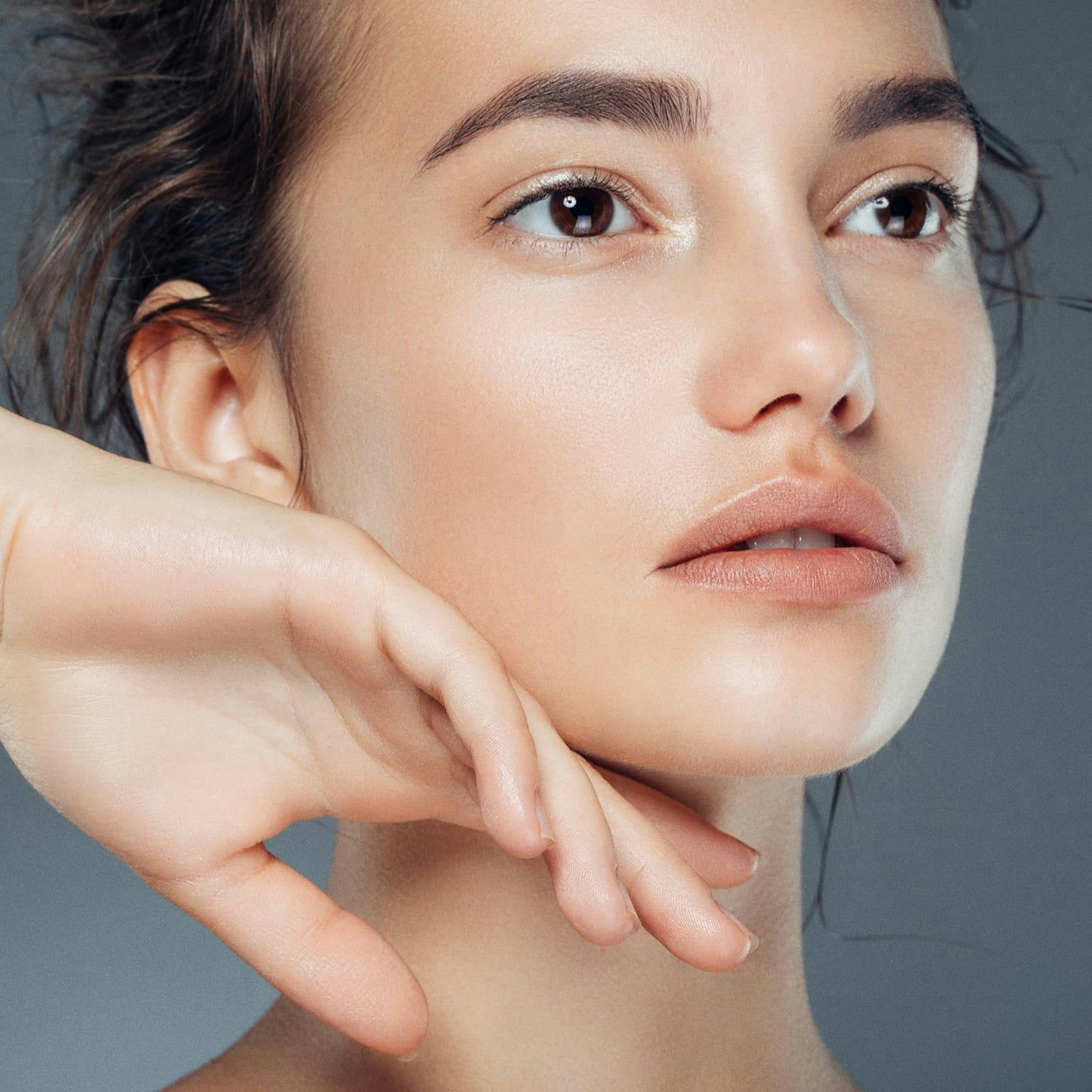 woman looking off to the right with hand relaxed against her jaw