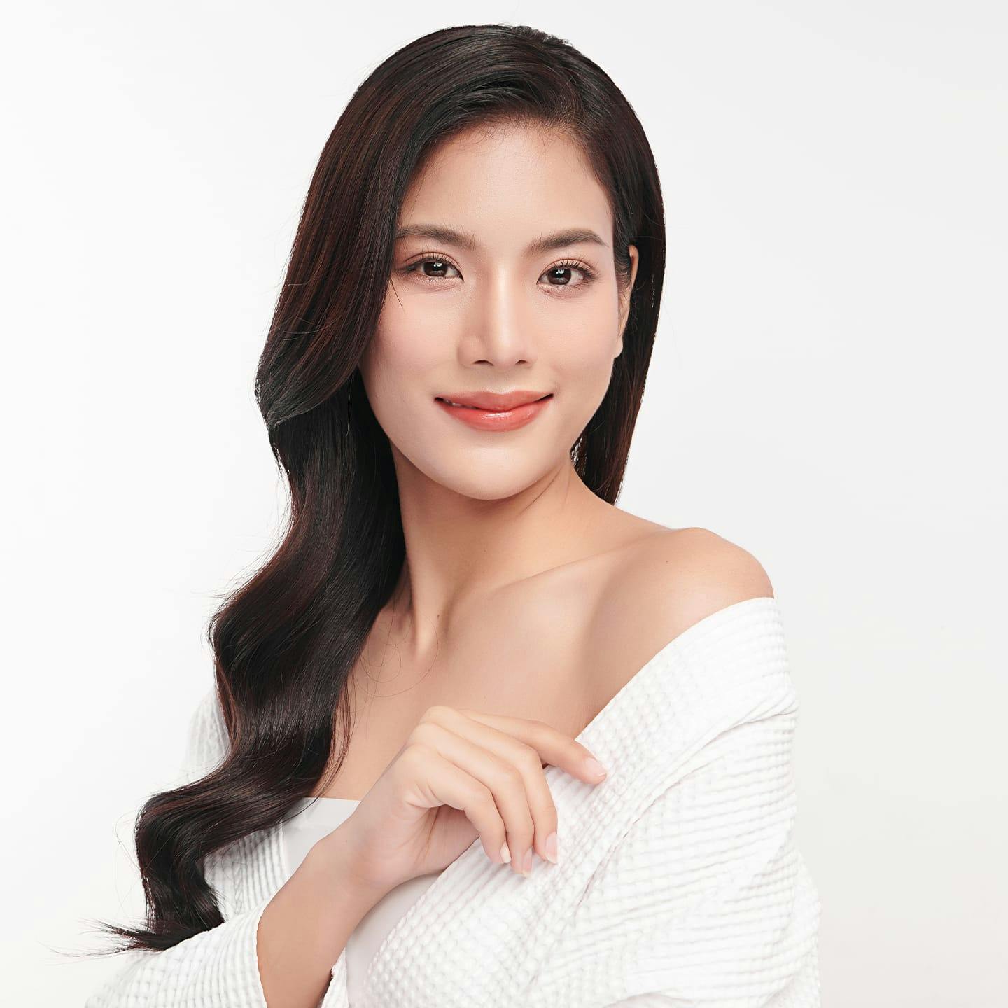 woman with wavy long hair smiling with white robe on