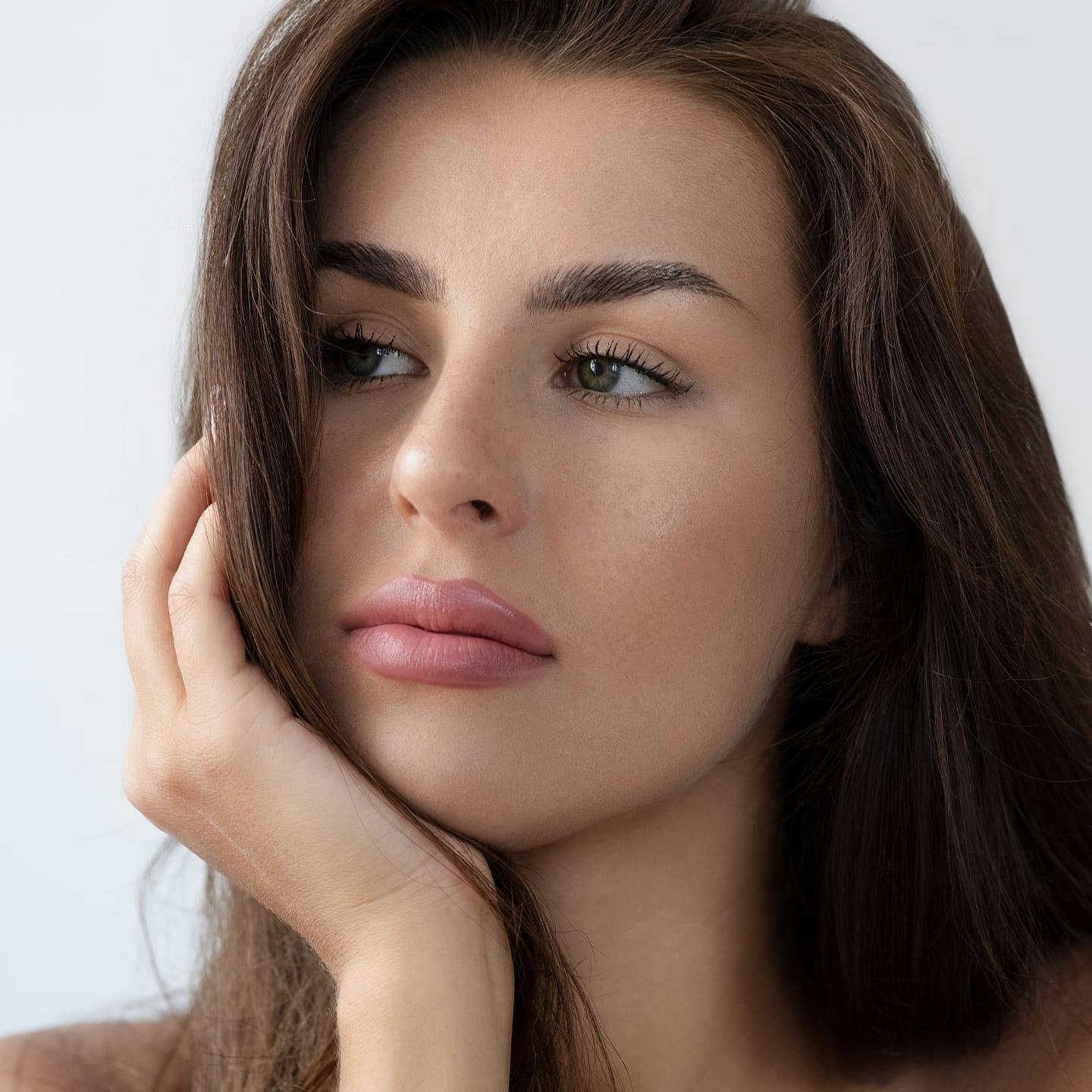 brunette woman resting chin in her hand