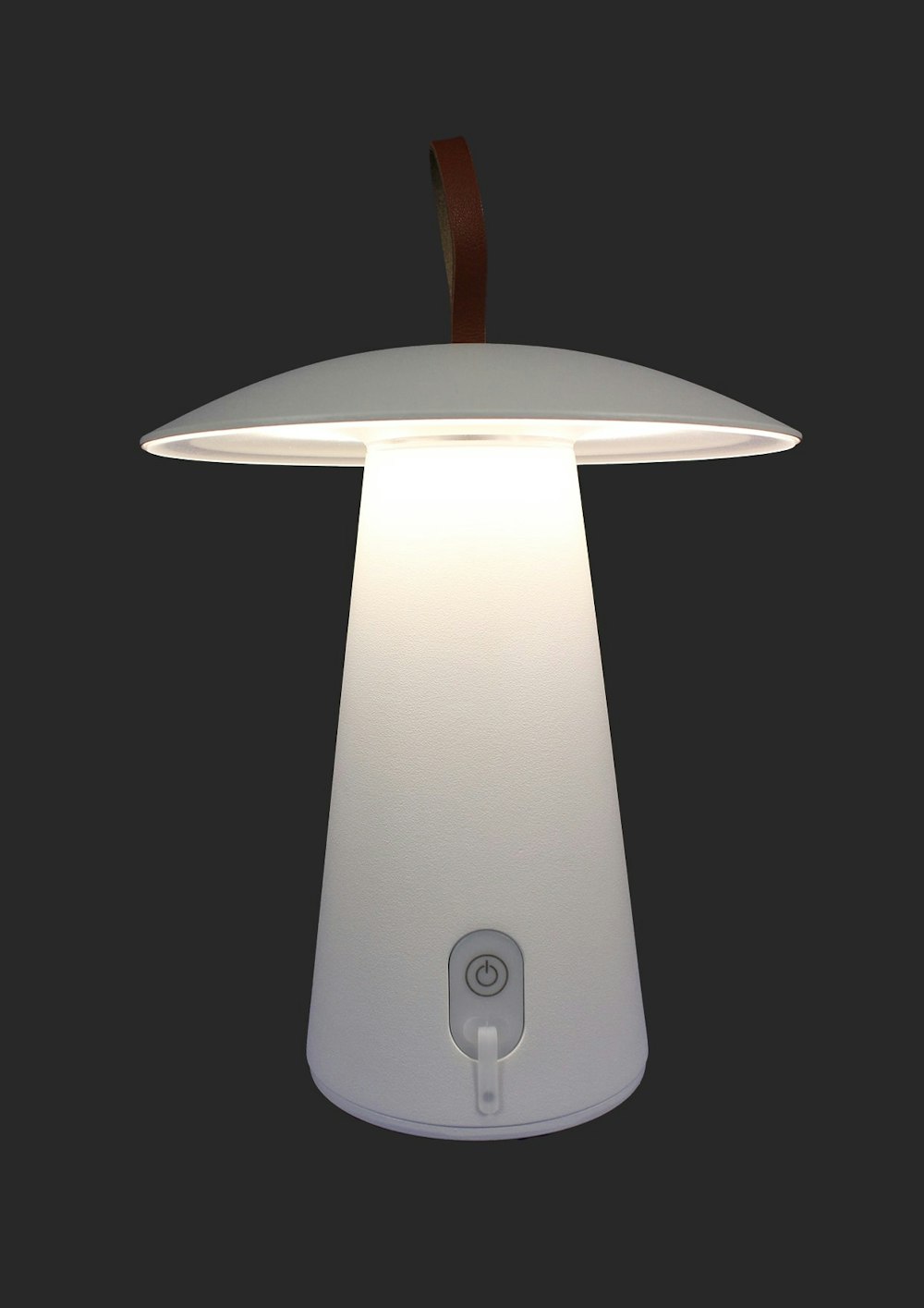 Moderne, weisse, pilzförmige Tischlampe mit braunem Lederband, die im Dunkeln leuchtet; Einschaltknopf und kleiner Fussschalter.