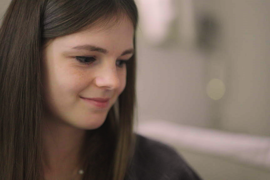 Britt kijkt schuin naar beneden en glimlacht