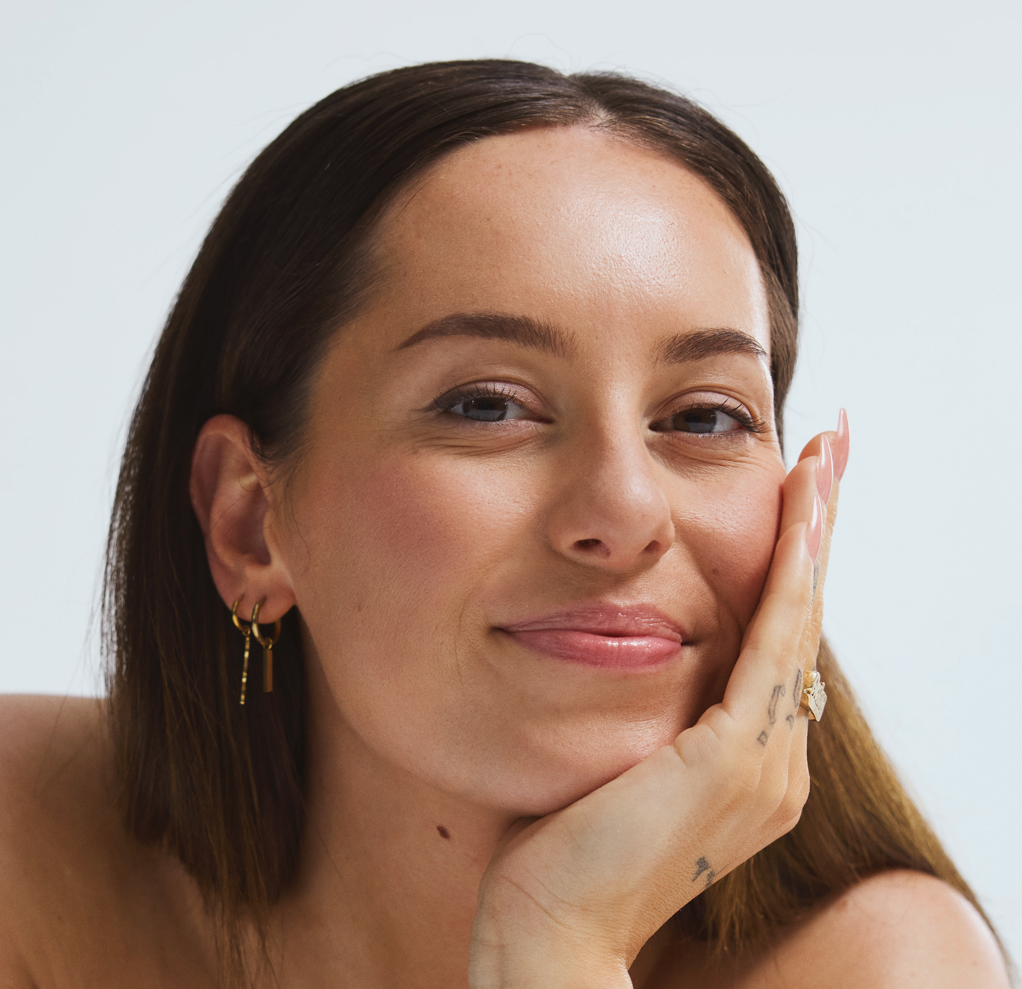 Gaby van LINDA.meiden met één hand onder haar kin kijkt lachend in de camera