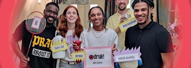 Vijf personen kijken lachend naar de camera en houden bordjes vast met gevoels erop