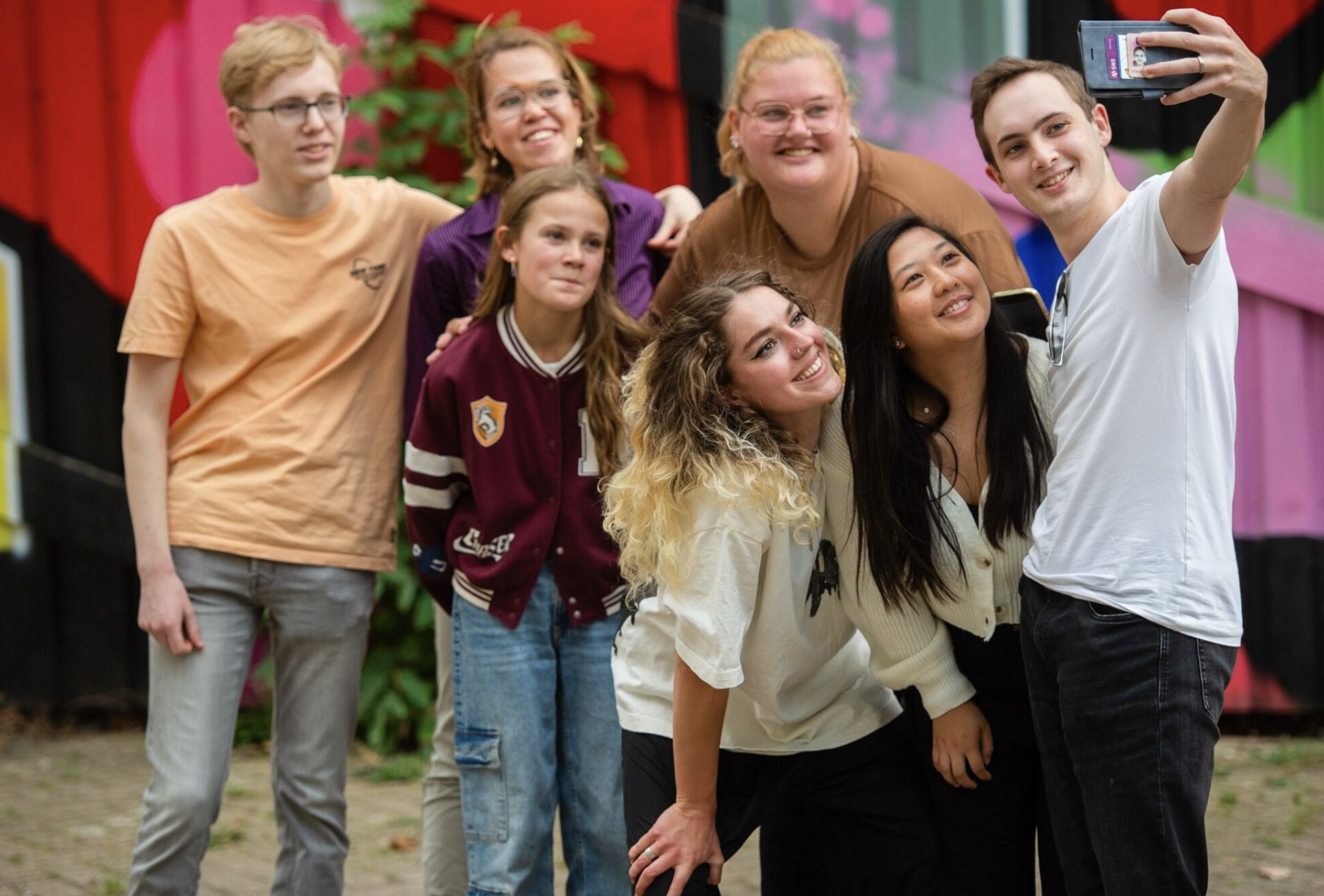 Groep lachende jongeren poseert buiten voor een selfie