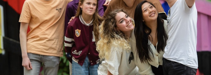 Groep lachende jongeren poseert buiten voor een selfie