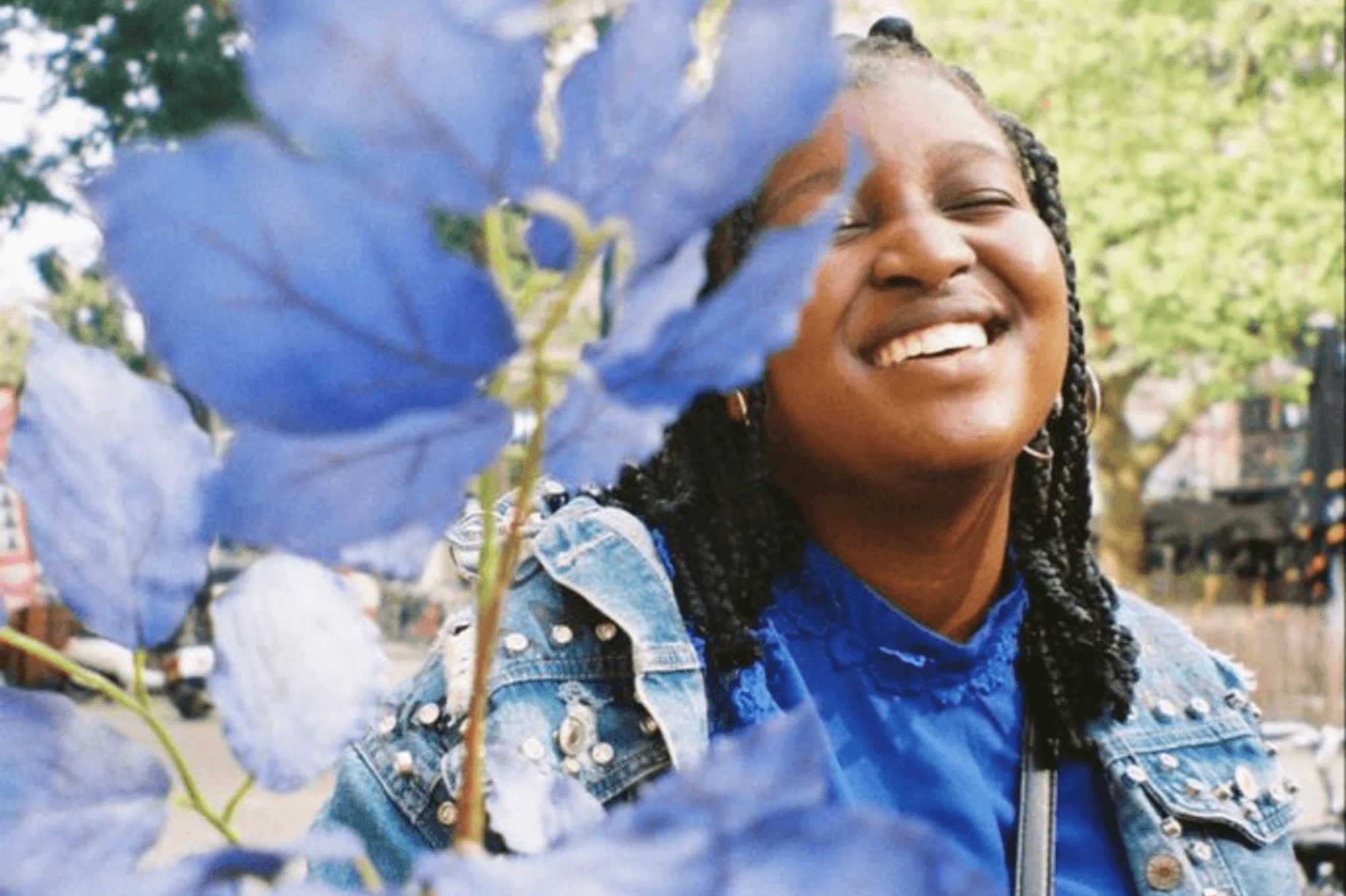 Nishaya staat lachend buiten naast een plant