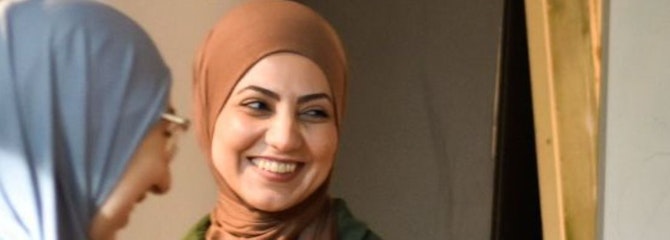 Halime en een vriedin staan voor een flipover en kijken lachend opzij