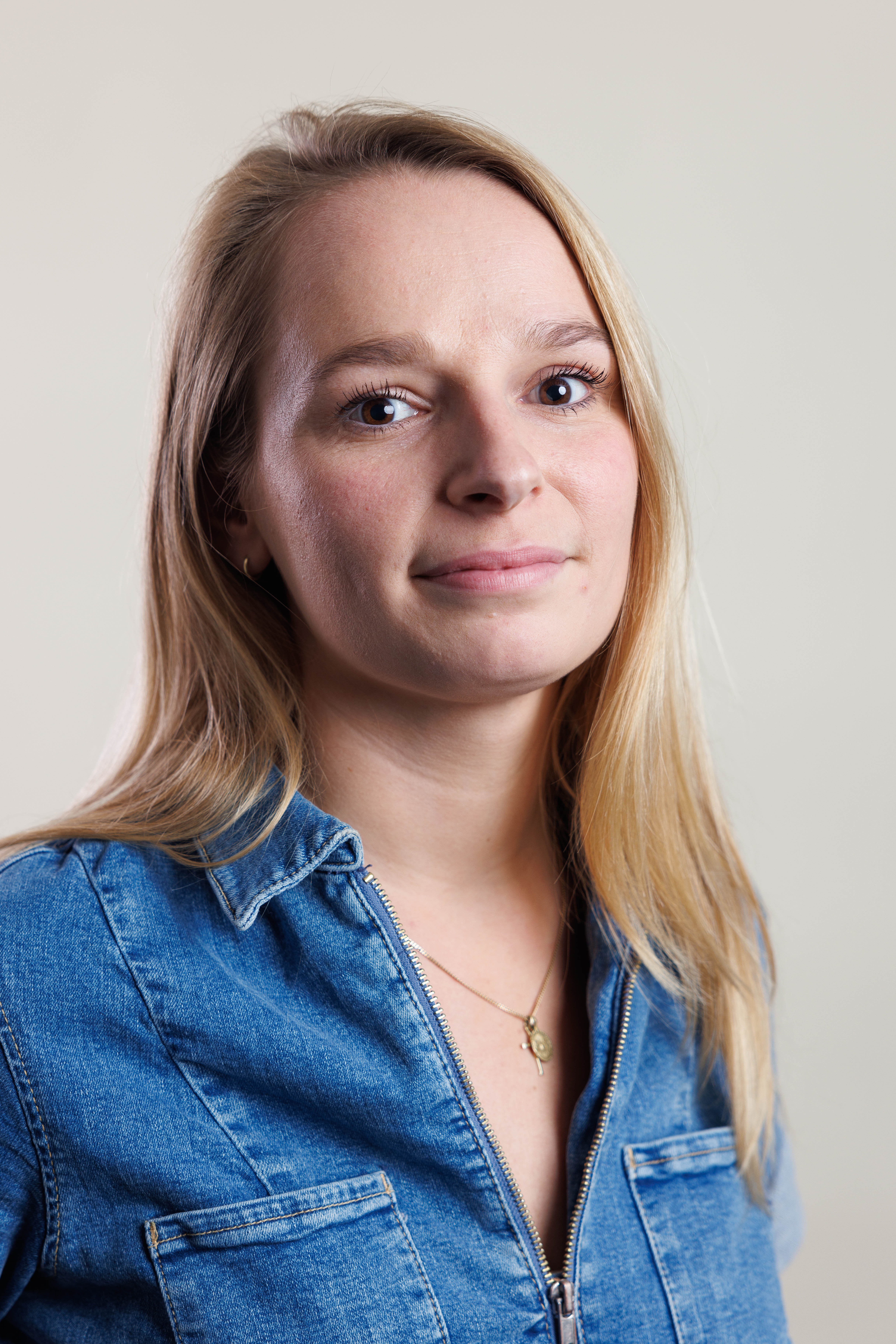 Juliette staat voor een witte muur en kijkt met een glimlach in de camera