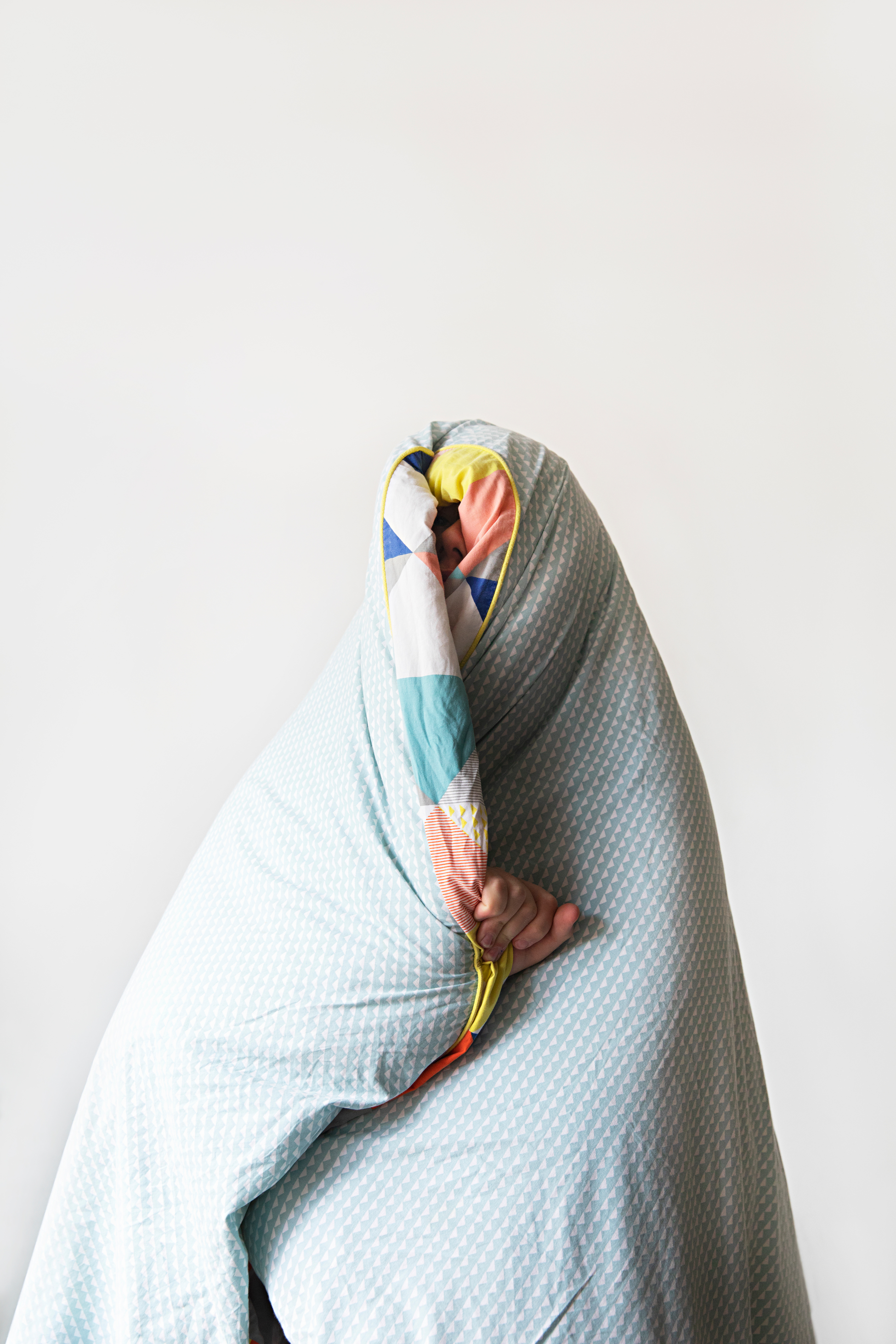 Een persoon bedekt zichzelf met een dekbed over zijn hoofd.