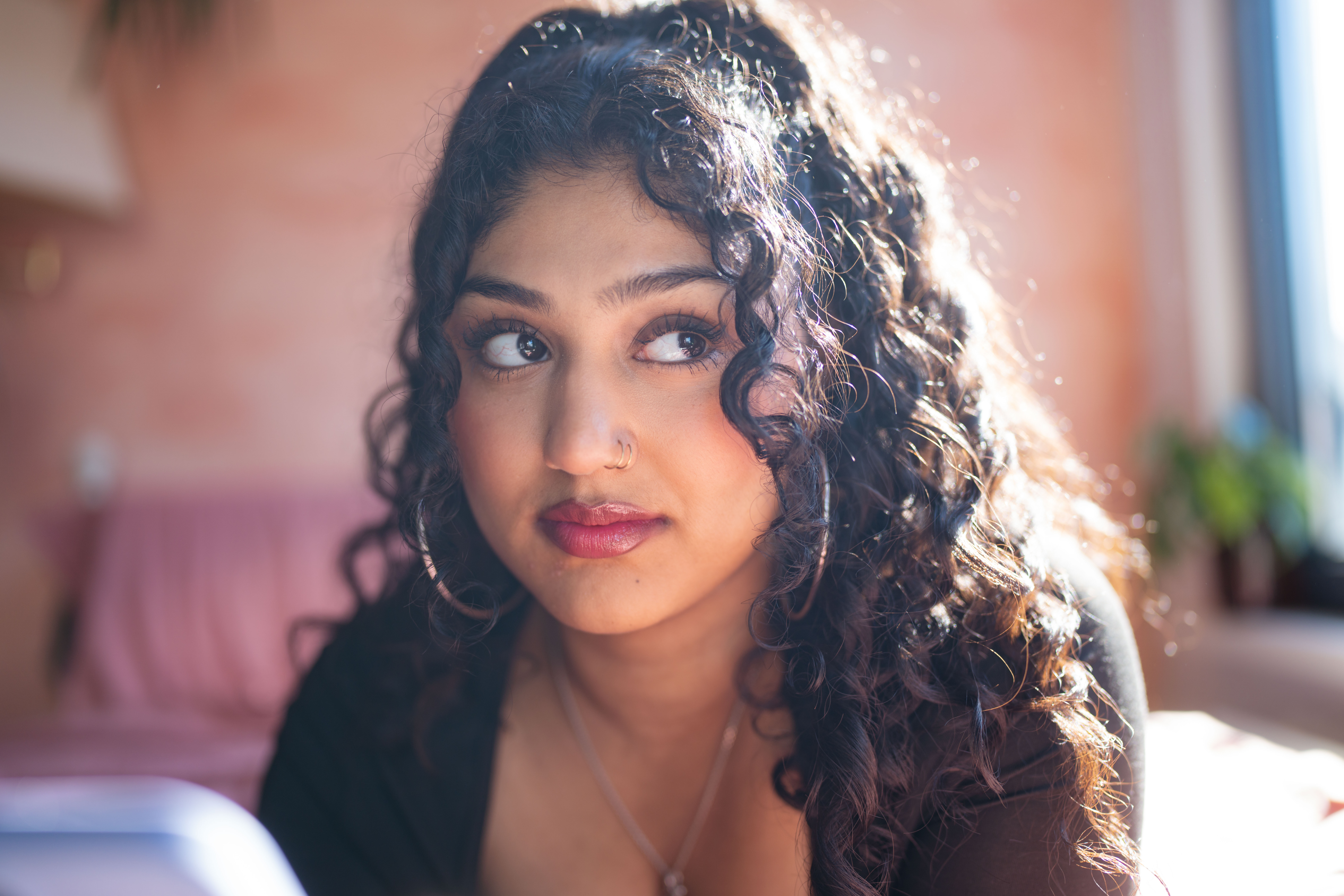 Jonge vrouw kijkt onzeker en twijfelend opzij in een zonverlichte, gezellige kamer